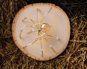 Golden beaded wire spider with shimmering champagne tones, pearl-like beads, and a clear crystal body for elegant handmade décor.